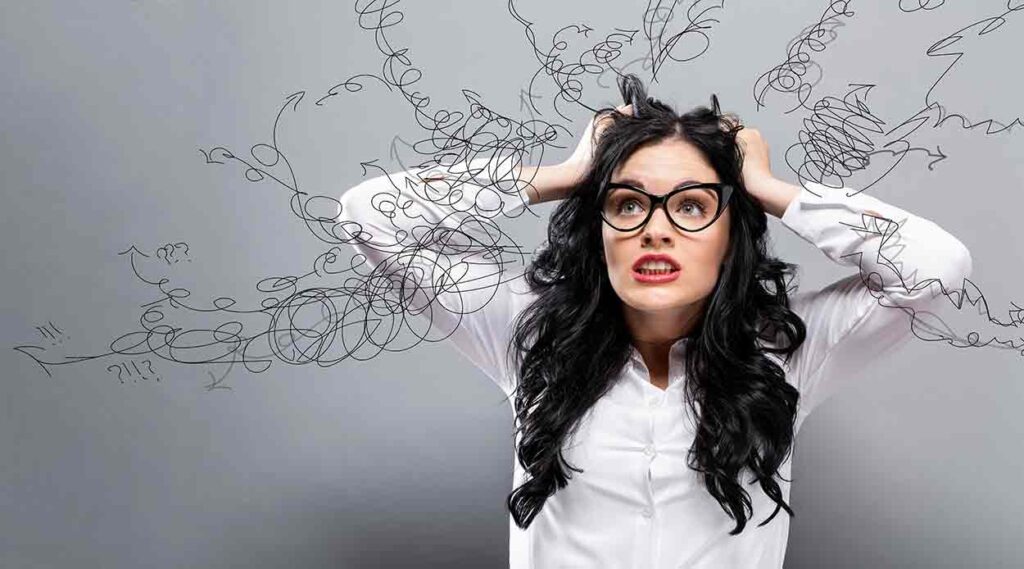 Stressed woman grabbing handfuls of hair on each side of her head.